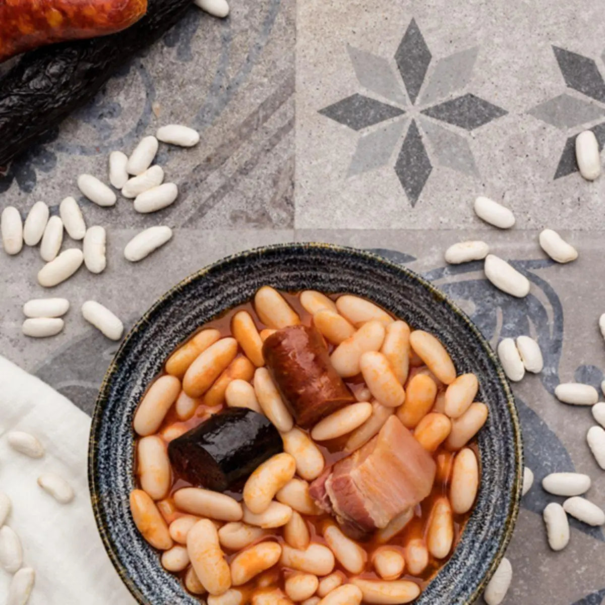 Ración humeante de fabada asturiana conservas arbeyal mostrando la legumbre entera y el compango.